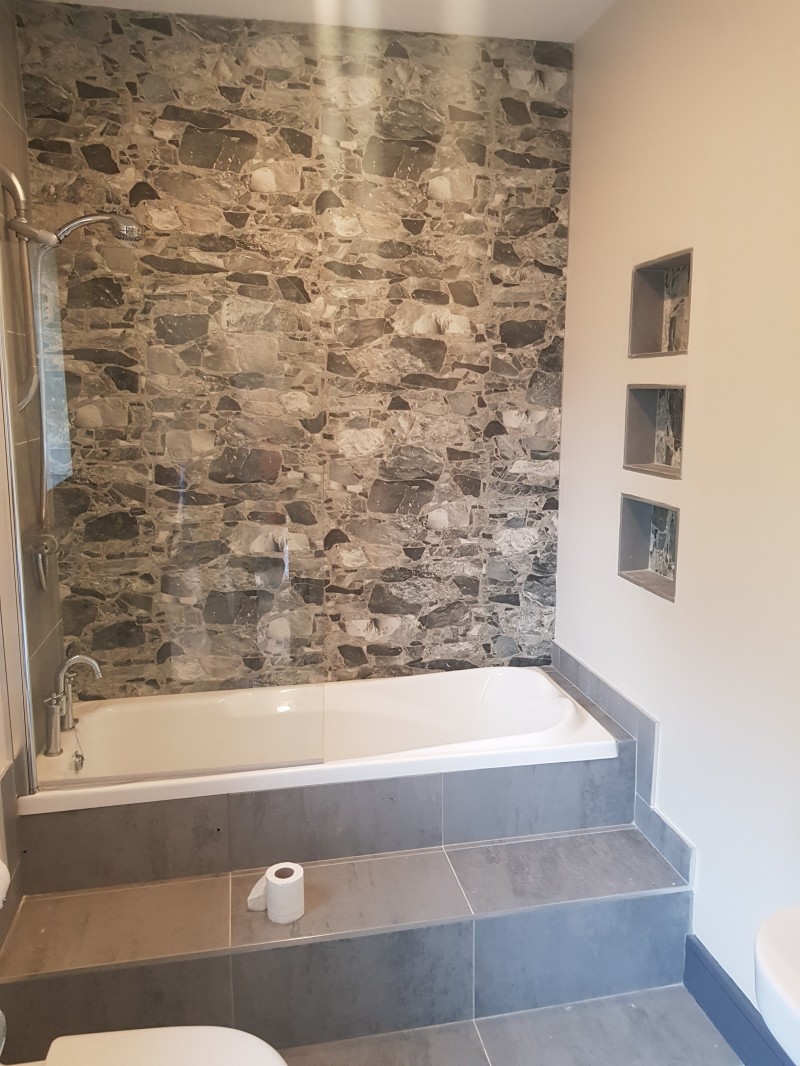 Stone effect wall tiles and inset bath in a new bathroom installation in Leitrim home by North West Tiles & Timber, Ireland